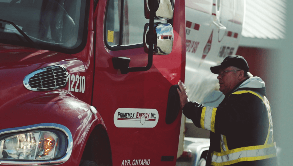 A photo of a fuel truck driver about to get into a Primemax Energy fuel delivery truck.